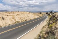 a road going down into the distance in the desert with a big sign on the other side