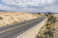 a road going down into the distance in the desert with a big sign on the other side
