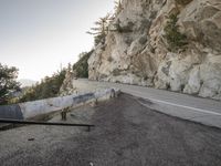 a car on a road in front of a cliff and a fence to make the roadway clear