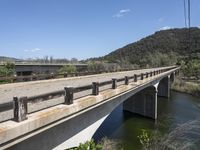 a view from a bridge overlooking trees and a mountain range of hills behind a bridge