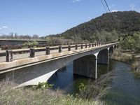 a view from a bridge overlooking trees and a mountain range of hills behind a bridge