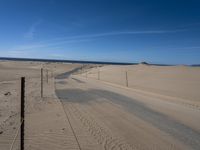 a paved beach with a fence in front of it and the ocean in the distance