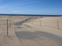 a paved beach with a fence in front of it and the ocean in the distance