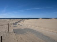 a paved beach with a fence in front of it and the ocean in the distance