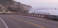 a highway that runs along a beach near the water and cliffs with waves on either side of it