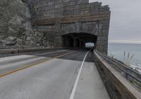 a tunnel and road running into the ocean with an ocean in the background on a gloom day