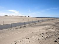 a paved beach with a fence in front of it and the ocean in the distance