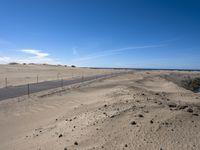 a paved beach with a fence in front of it and the ocean in the distance