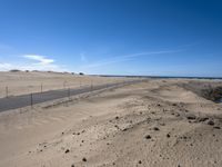 a paved beach with a fence in front of it and the ocean in the distance