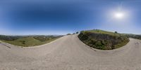 a 360 - camera view of a road going through the hills and at sunset in the background