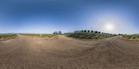 two panoramas of a dirt road in a field with grass on either side and bushes on each side