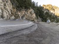 a motorcycle parked along the side of a road next to a cliff filled with forest