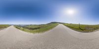 a panorama fisheye lens picture with the sky above it and mountains behind it with one person riding a skateboard on it