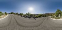 a long empty street in front of a mountain range, as seen from a fisheye lens