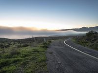 road and mountains at sunrise over foggy area in hilly country with sky and mountains in distance