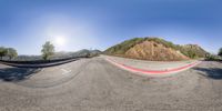 the camera has a view down a street through a 360 - ray lens as a skateboarder performs tricks