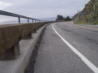 an empty road on a cliff side next to the ocean and shore line near some rock cliffs