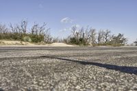 a view along a dirt road of an empty field and mountains in the distance of the scene