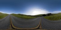 a couple of road splits in the middle of a grassy hillside with hills in the distance