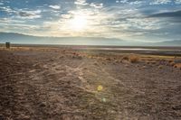 there is a person sitting on the bench at sunset in the desert area, overlooking an open field