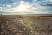 there is a person sitting on the bench at sunset in the desert area, overlooking an open field