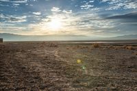 there is a person sitting on the bench at sunset in the desert area, overlooking an open field