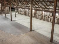 a big, empty, unfinished barn with beams and wood floors and wood ceilinging