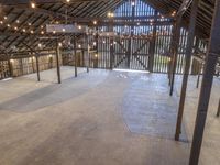 the inside of a barn with lights hanging from the ceiling and many wooden beams, which hold more than two floors