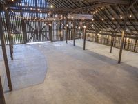 the inside of a barn with lights hanging from the ceiling and many wooden beams, which hold more than two floors