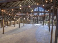 the inside of a barn with lights hanging from the ceiling and many wooden beams, which hold more than two floors