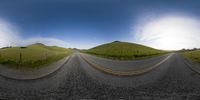 a curved road going down towards two grassy hills with mountains in the background in 3d graphics