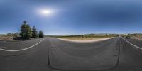 360 view image of a road with sun in the background and car driving on it