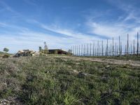 the small hut on a hill with large poles in the background is empty and grass is around it