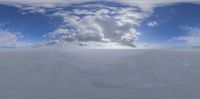 a panoramic photo of clouds and snow in the sky above a small mountain