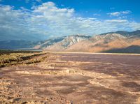 shadow of a person standing on the ground in front of mountains and water filled desert