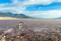 there is an empty lake with rocks scattered about it in the middle of the desert