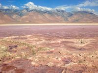 an area that is covered with red, brown and green dirt that looks like sand