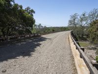 a view from a bridge overlooking trees and a mountain range of hills behind a bridge