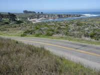 a person riding a skate board on a scenic road near the ocean during the day