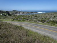 a person riding a skate board on a scenic road near the ocean during the day