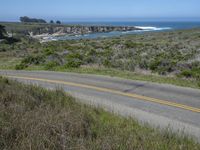 a person riding a skate board on a scenic road near the ocean during the day