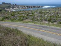 a person riding a skate board on a scenic road near the ocean during the day