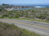 a person riding a skate board on a scenic road near the ocean during the day