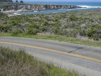 a person riding a skate board on a scenic road near the ocean during the day