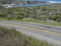 a person riding a skate board on a scenic road near the ocean during the day