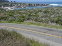 a person riding a skate board on a scenic road near the ocean during the day