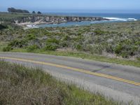 a person riding a skate board on a scenic road near the ocean during the day