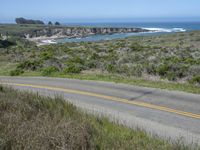 a person riding a skate board on a scenic road near the ocean during the day