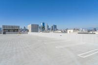 a parking lot next to a building with a city skyline in the background at the foreground