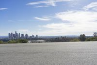 an adult woman with sunglasses riding a motorcycle and looking at a city skyline from a viewpoint